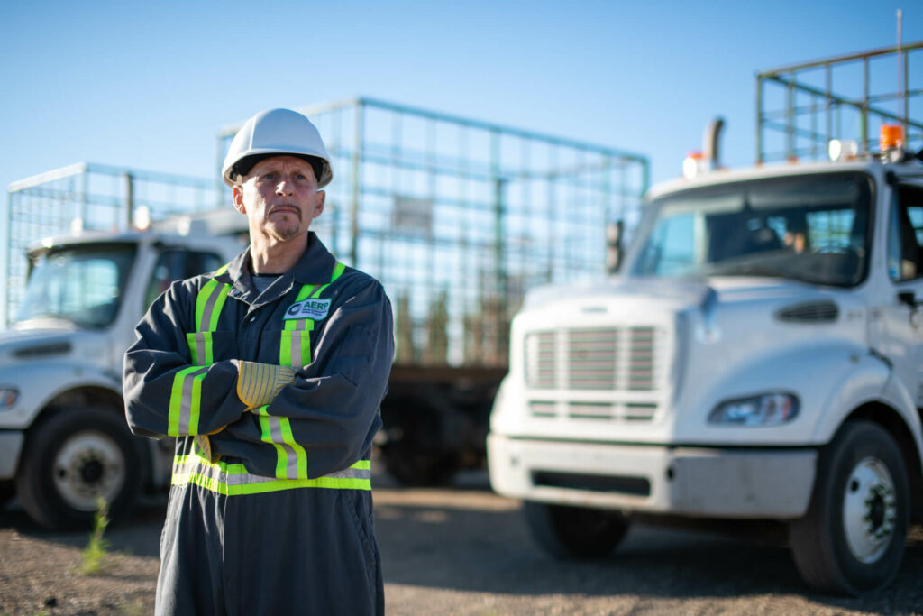 Picture of a construction worker in a hard hat in front of a blury fleet of trucks